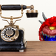 A pixelated demon eyes a rotary telephone.